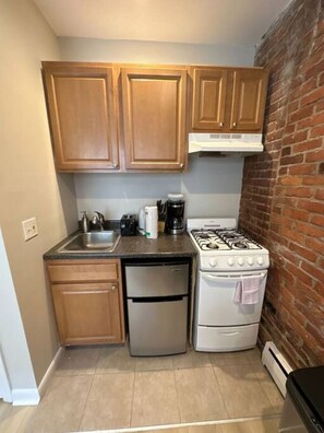 Een oven, een koffiezetapparaat/waterkoker, kookgerei, borden en bestek