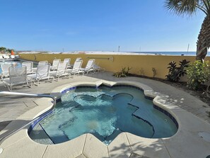 A hot tub with a curved edge, surrounded by lounge chairs and a tiled deck. - 🏖️Fabulous Gulf Views | Seasonal Beach Service | Pelican Isle 202🐚 (Fort Walton Beach)