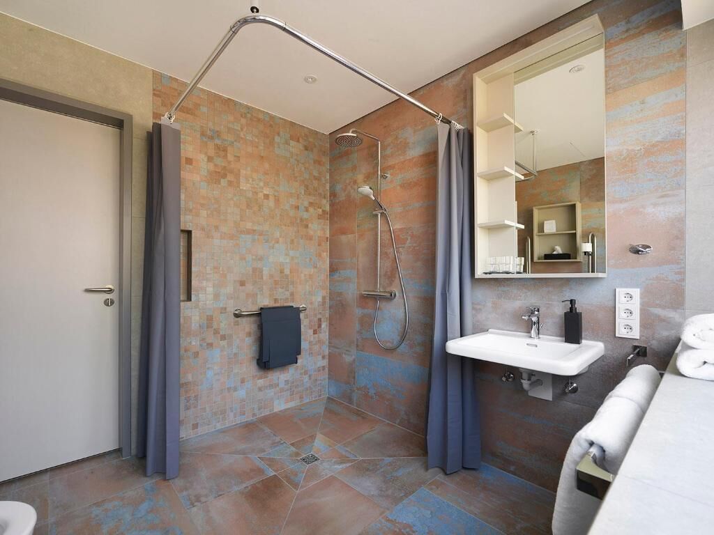 Un baño moderno con ducha, lavamanos y espejo.
