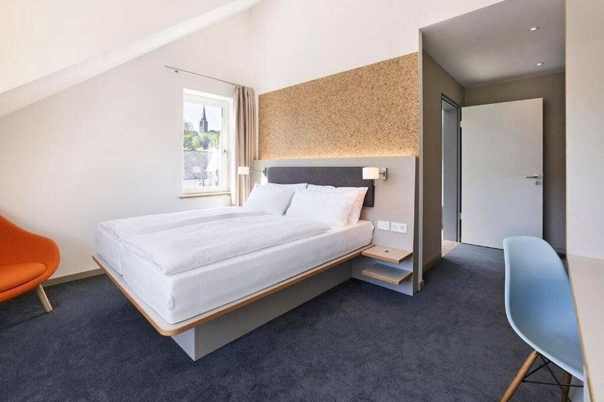 Moderni hotellihuone, jossa on sänky, työpöytä ja tuoli.