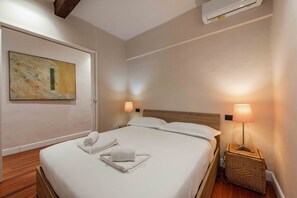 Ein Hotelzimmer mit einem Bett, einer Wandklimaanlage, einer Lampe und einem Gemälde.