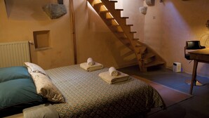 Een slaapkamer met een houten trap, een bed met beddengoed met een patroon en een bureau met een stoel.