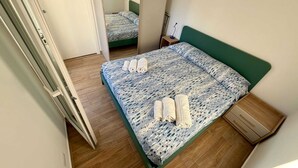 Une petite chambre à coucher, bien rangée, avec un lit, une table de chevet et une armoire en bois.