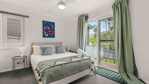 A bedroom with a bed, a bedside table, a lamp, a window with curtains, and a painting on the wall. - Blenheim Breeze by Experience Jervis Bay (Vincentia)