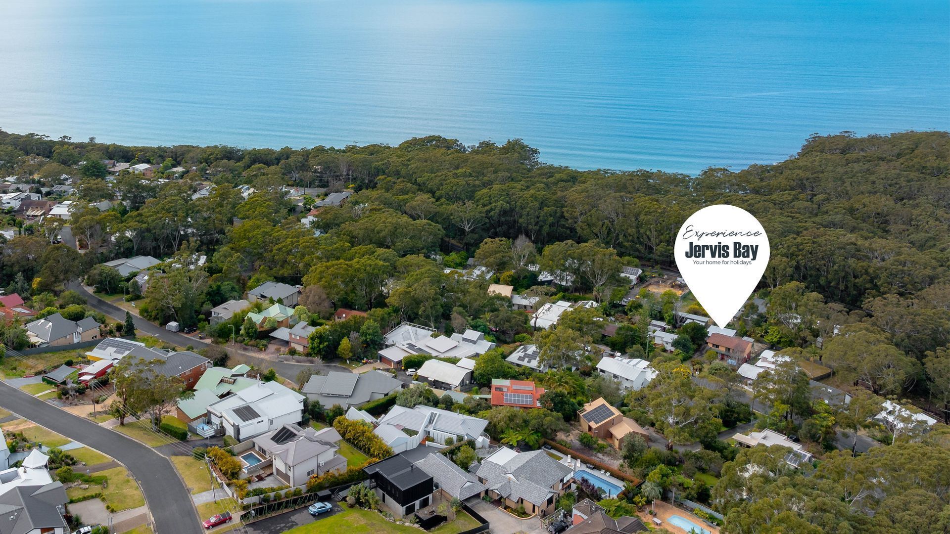 An aerial view of a residential area with houses, roads, and a large body of water.