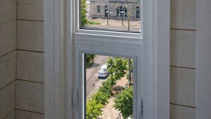 Ein Zimmer mit Fensterblick auf ein Gebäude mit einem Glockenturm und eine Straße mit Autos.