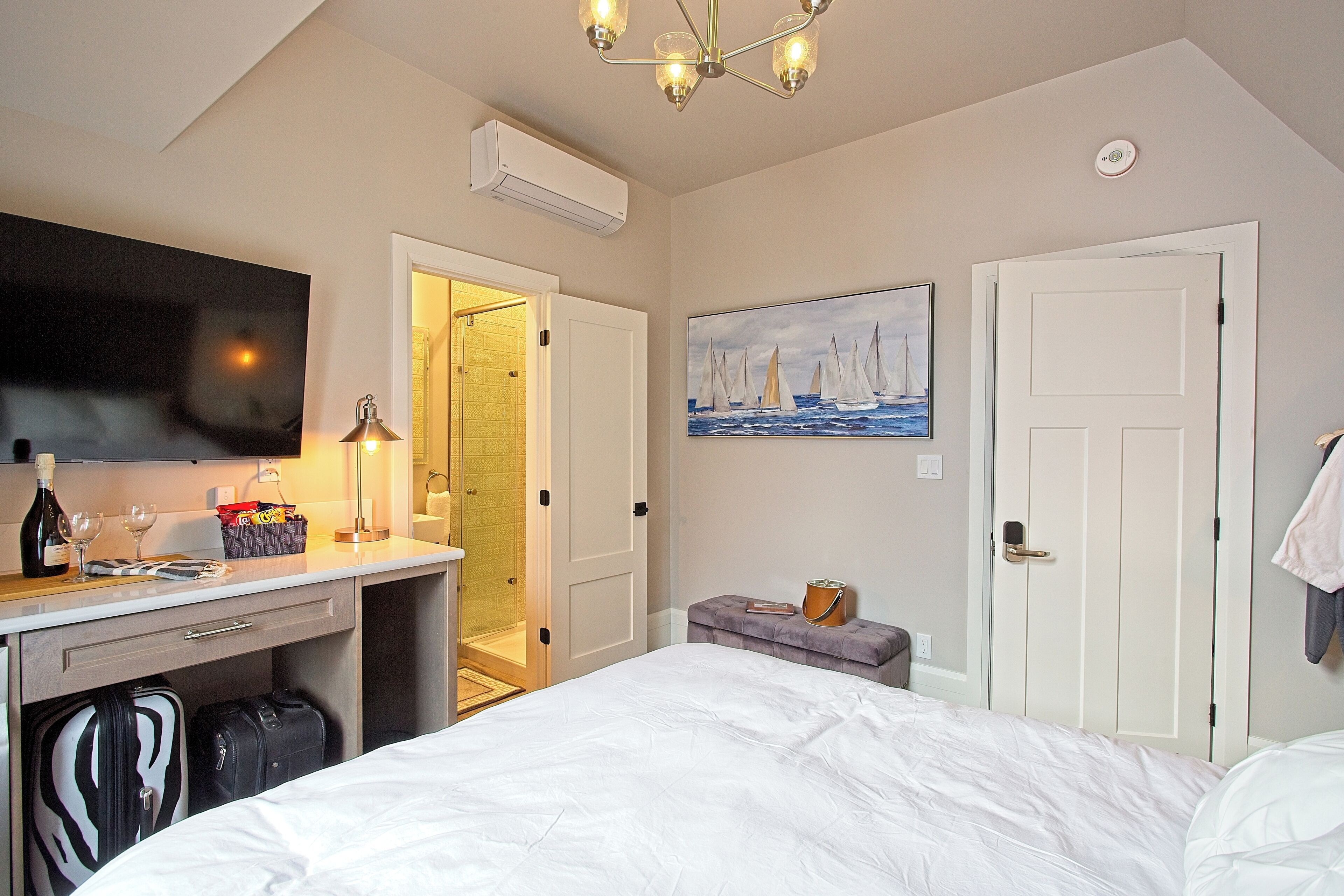 Une chambre d’hôtel comprenant un lit, un bureau avec un téléviseur à écran plat, un tableau et une armoire.