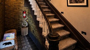 Eine Treppe mit Holzwand, einer Kristallleuchtre und gerahmten Bildern an den Wänden.