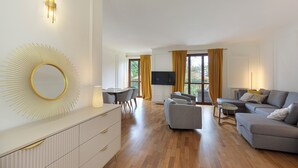 A modern living room with a sofa, a dining area with chairs, a TV, and a large mirror. - Raphael Stresa (Stresa)