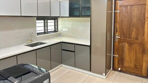 A kitchen with a sink, cabinets, a window, and a wooden door.