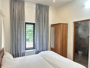 Une chambre à coucher comprenant un lit, une armoire, une fenêtre avec des rideaux et un espace douche.