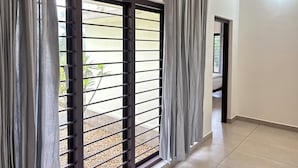 A room with a sliding glass door, a tiled floor, and a view of a garden.