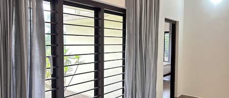 A room with a sliding glass door, a tiled floor, and a view of a garden.