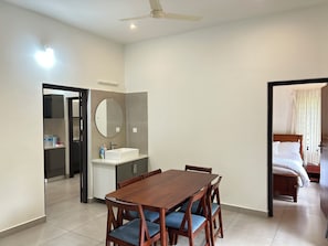 A hotel room with a dining area, a bathroom with a mirror, and a bed.
