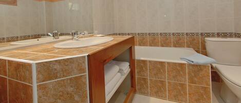 A bathroom with two sinks, a bathtub, and a toilet.