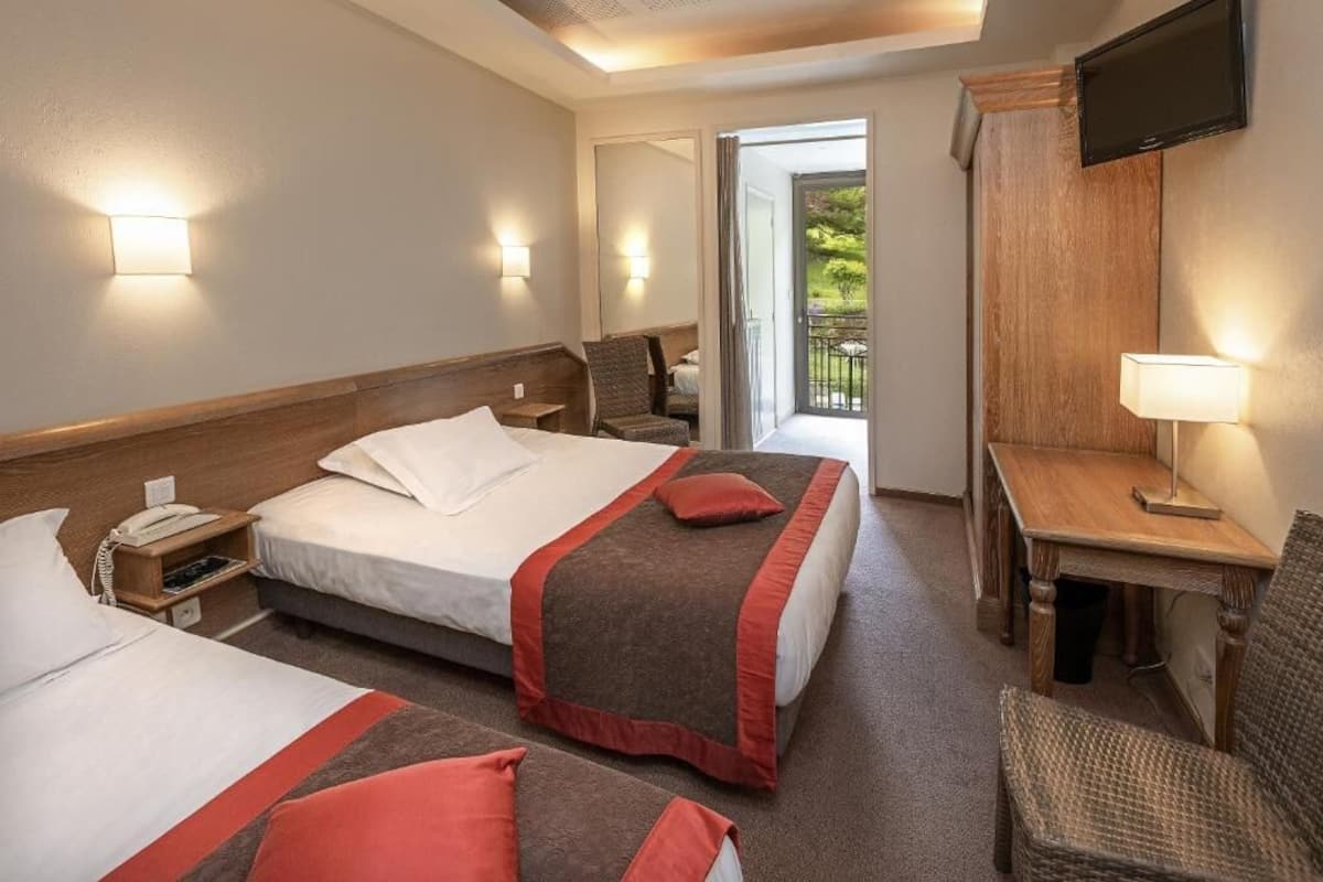 Une chambre d’hôtel avec deux lits, un bureau, une chaise, une télévision et un balcon avec vue.