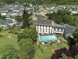 Vista aérea de uma área residencial com um edifício grande com piscina, cercado por vegetação e outras casas.