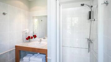 A modern bathroom with a glass-enclosed shower, a wooden vanity with a sink, and a mirror.