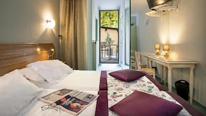 A hotel room with a bed, a desk, a television, and a view of the outdoors.