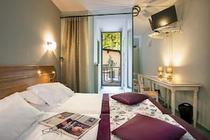 Quarto de hotel com cama, escrivaninha, televisão e vista para o exterior.