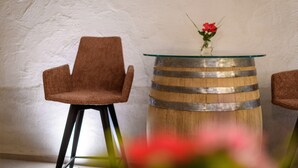 Ein Zimmer mit einem runden Holzbottich, einem Tisch mit Glasplatte und zwei braunen Stühlen.