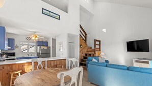 Eine moderne Küche mit Holzausstattung, einem Esstisch und einem blauen Sofa im Wohnbereich.