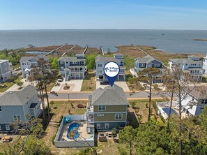 A residential area with multiple houses, a swimming pool, and a view of the ocean. - Sound Legacy: Private Pool and Hot Tub (Corolla)
