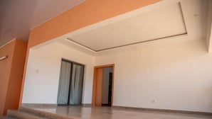 A modern interior with a staircase leading to a door, a visible ceiling with recessed lighting, and a plain wall.