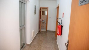 A hallway with a fire extinguisher mounted on the wall, a door labeled "Suite 2", and a window on the left.