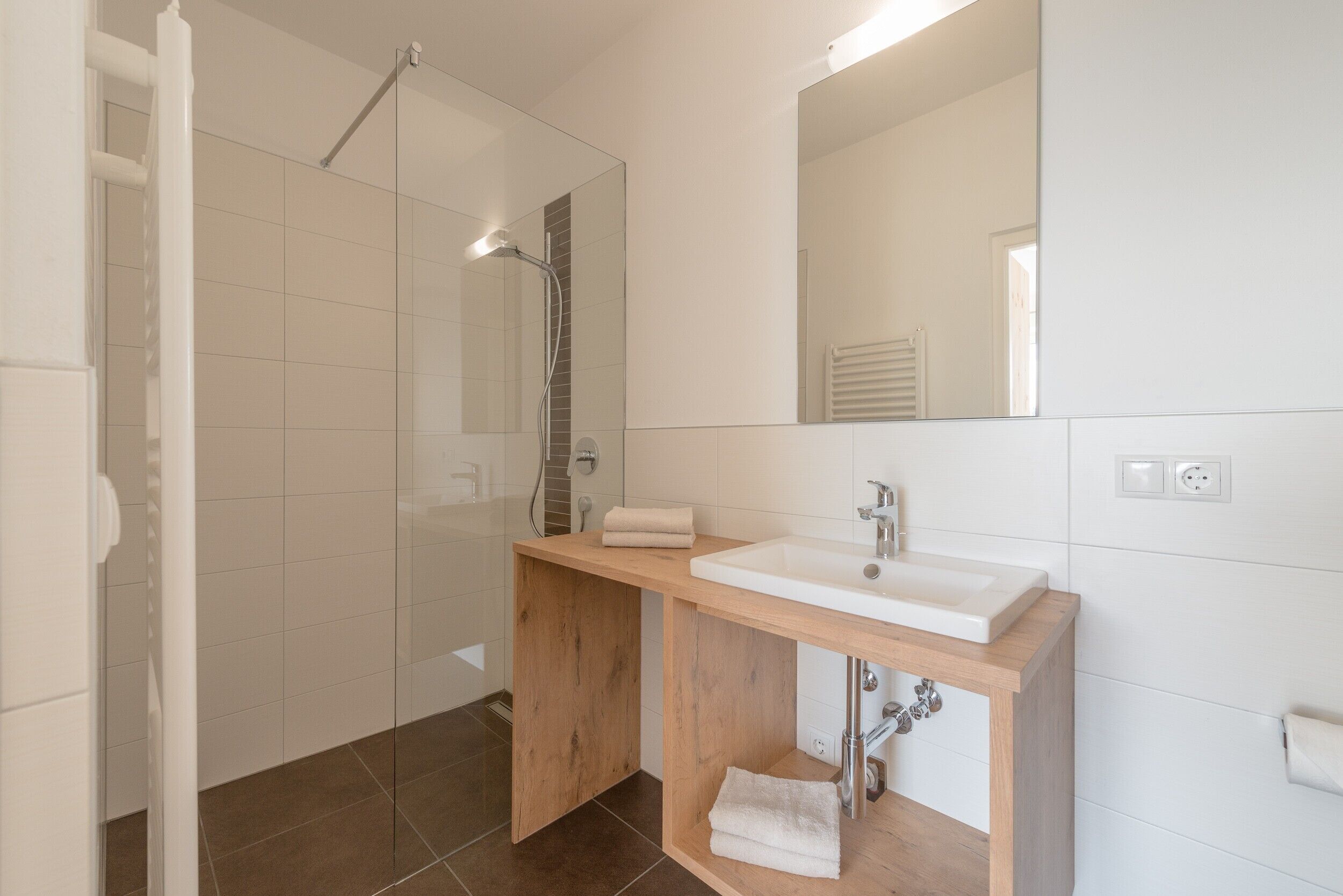 Ein modernes Badezimmer mit Dusche, Waschbecken und Spiegel.