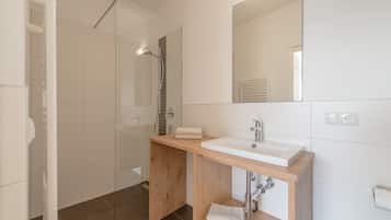 Ein modernes Badezimmer mit Dusche, Waschbecken und Spiegel.