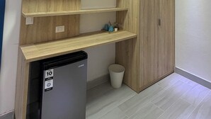 Een compacte keuken met houten kastjes, een geïntegreerde koelkast en een prullenbak.