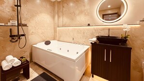 Een moderne badkamer met een vrijstaand bad, een handdouche, een ronde spiegel met verlichting en een donker houten kastje.