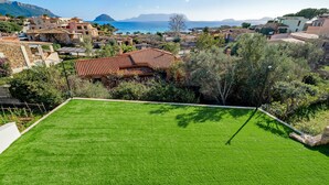 A residential area with a well-maintained lawn, stone walls, and Mediterranean-style houses.