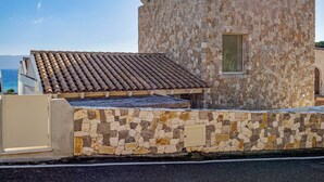 A stone building with a tiled roof, a small window, and a gate.