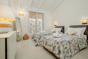 Une chambre avec deux lits, une table de chevet, une lampe, un miroir et un mur en pierre.