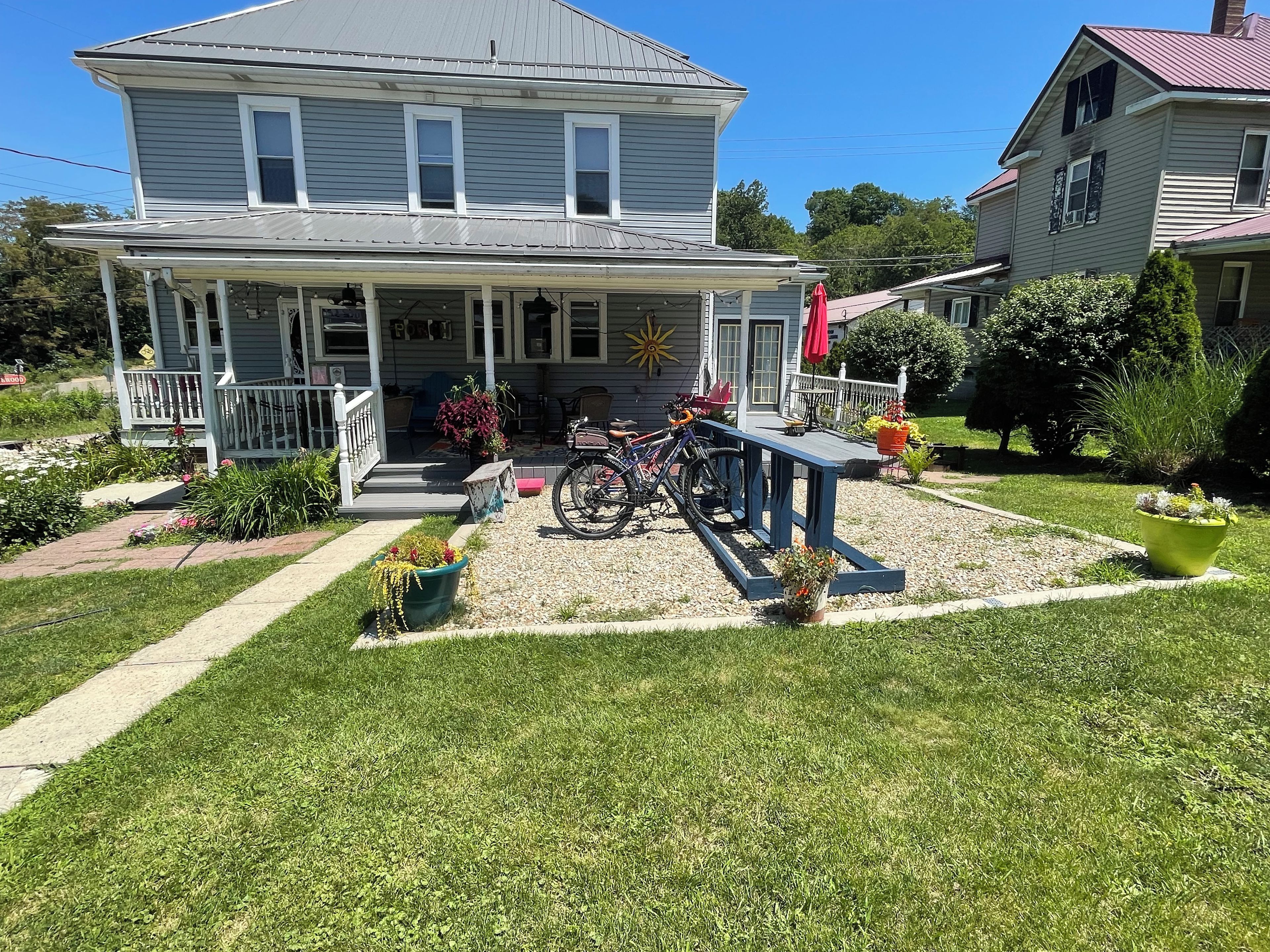 A two-story house with a porch, a bicycle, and a garden.
