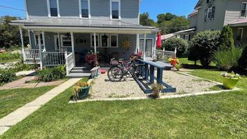 A two-story house with a porch, a bicycle, and a garden.