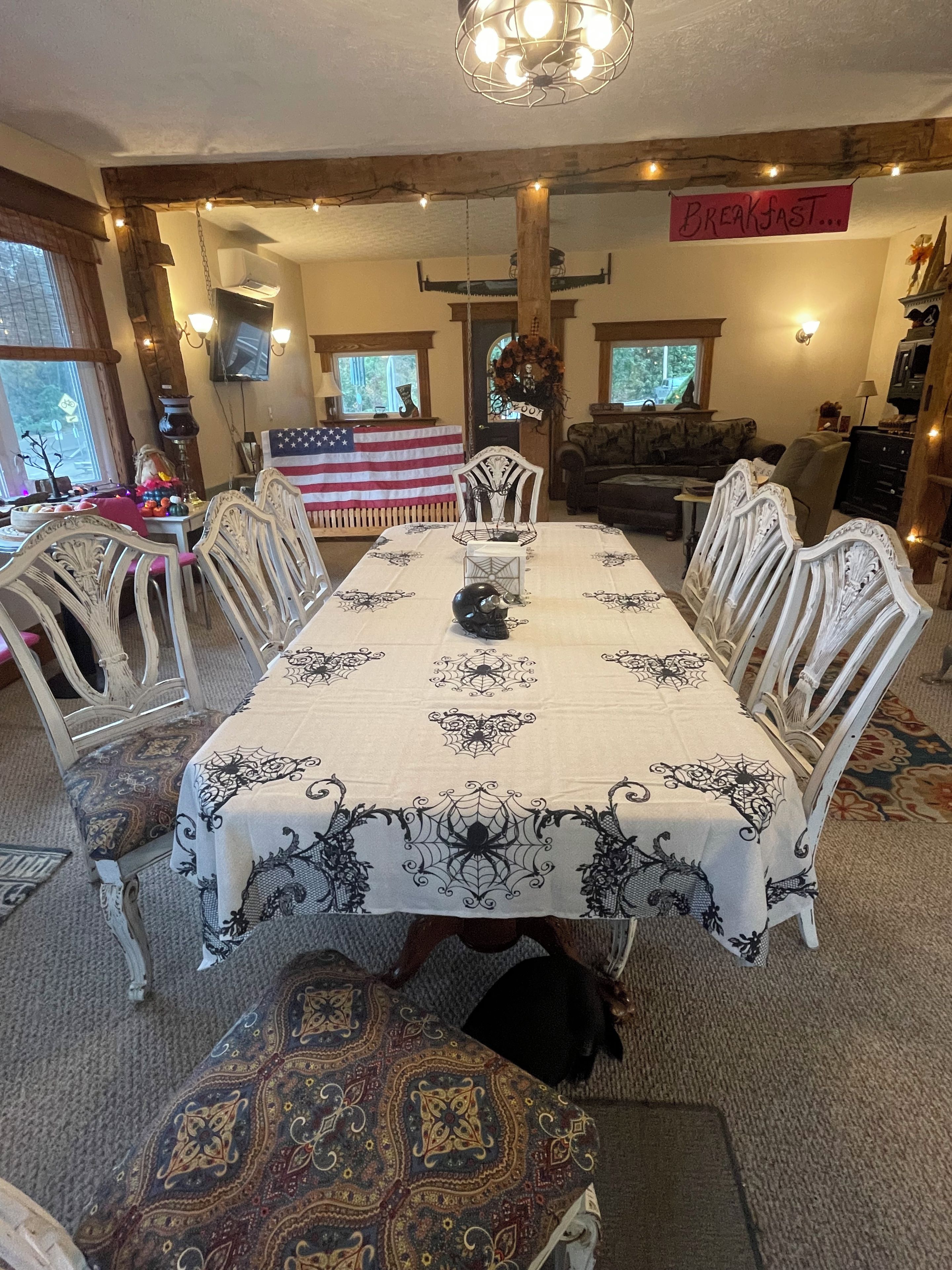 A dining area with a table set for breakfast, surrounded by chairs, and an American flag on the wall.