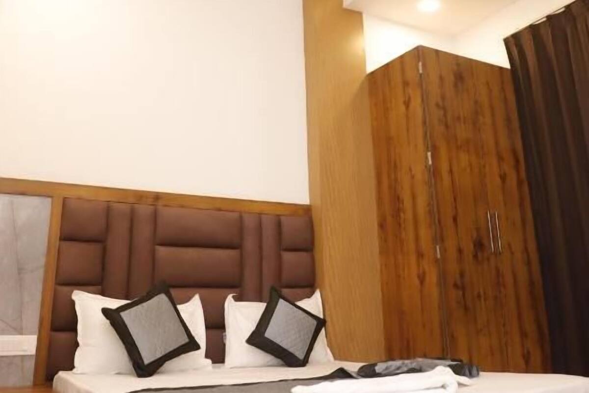 A bedroom with a wooden headboard, a bed with white bedding, a wooden wardrobe, and a ceiling fan.