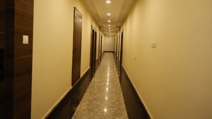 A long, narrow hallway with wooden paneling on one side and a marble floor. - THE BLESSING PALACE (Muzaffarpur)