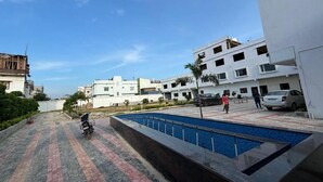 A residential area with a paved walkway, a swimming pool, and modern buildings. - THE BLESSING PALACE (Muzaffarpur)