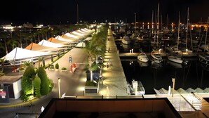Un port de plaisance avec des bateaux amarrés, une promenade piétonne et une rangée de tentes.