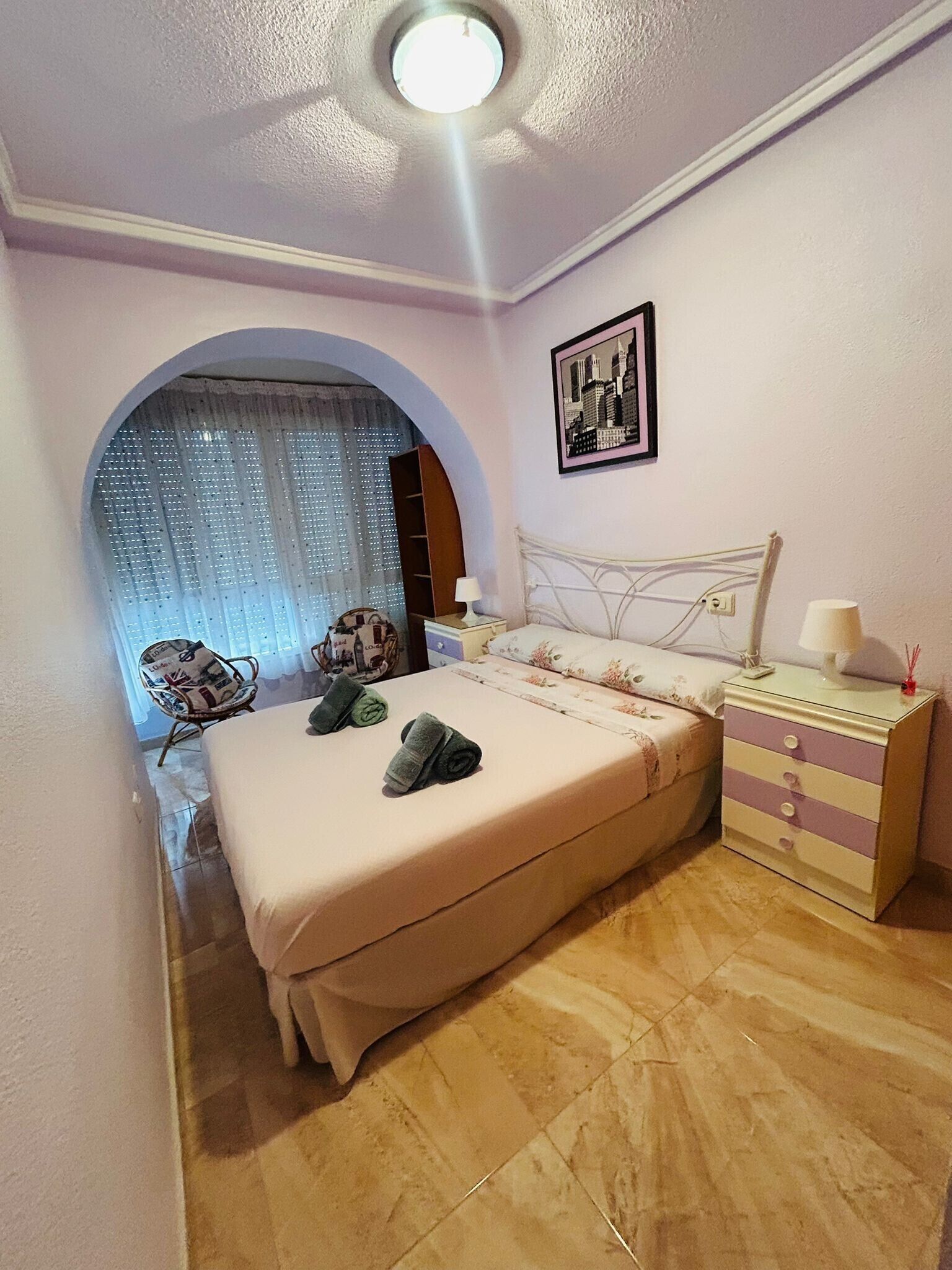 A bedroom with a bed, a dresser, a chair, and a window with curtains.