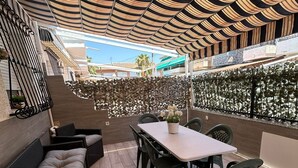 Une terrasse extérieure avec une table et des chaises, un canapé et un mur décoratif.