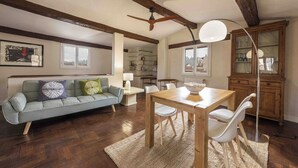 A living room with a sofa, dining table, chairs, a ceiling fan, and a cabinet. - Casa Musa by MMega (Florence)