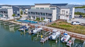 Uma marina com barcos atracados, piscina e edifícios modernos com varandas.