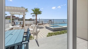 Uma área de piscina com vista para o oceano, mobiliário ao ar livre e um pergolado.