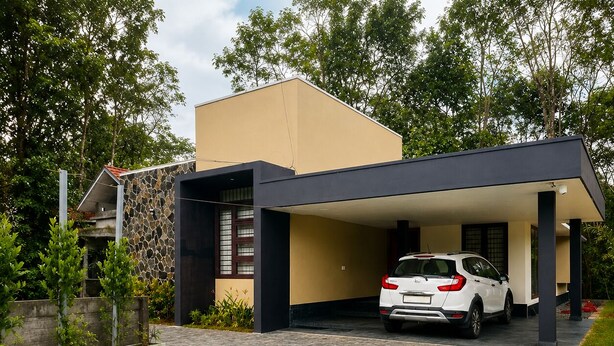 Una casa moderna con piscina, un garaje techado y un muro de piedra.