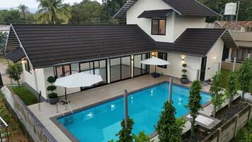 A modern house with a swimming pool, large windows, and a covered patio area.